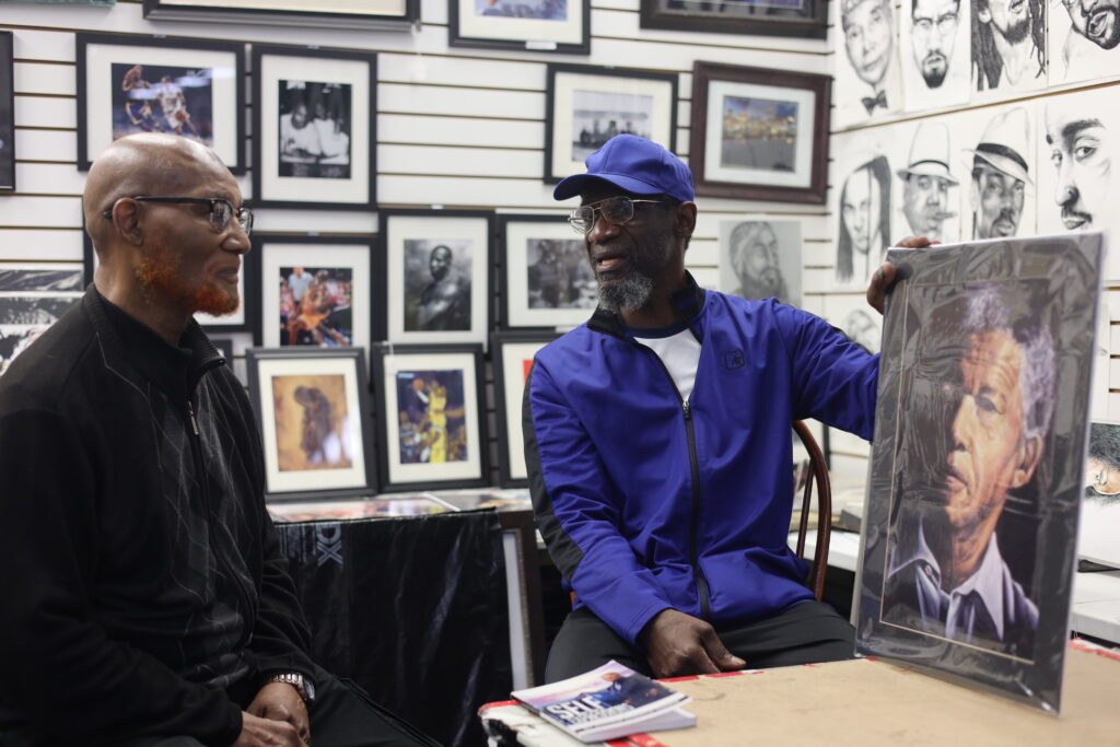 Longtime friends Donald Shakir, left, and Larry Owens, right, have used creative expression to help manage their mental heath after each was released from prison. Here, they are chatting at a booth at the Patapsco Flea Market in Baltimore, Maryland, where Owens sells his work. Photo credit: Jimae Hayes
