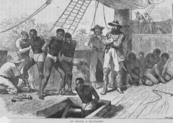 Enslaved people aboard a ship being shackled before being put in the hold. Illustration by Swain (Photo by Rischgitz/Getty Images)