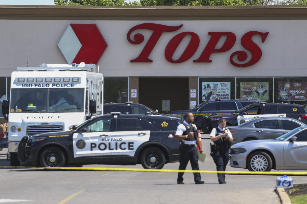 Police walk outside the Tops grocery store on Sunday, May 15, 2022, in Buffalo, New York. Payton Gendron was sentenced to life in prison Wednesday, Feb. 15, 2023, for killing 10 people at a Buffalo supermarket in an attack fueled by racist conspiracy theories he encountered online. Photo credit: Joshua Bessex, The Associated Press 