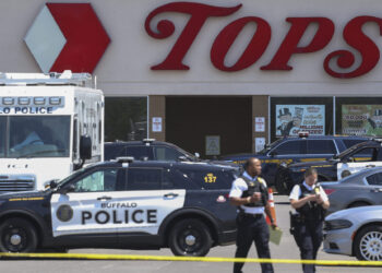 Police walk outside the Tops grocery store on Sunday, May 15, 2022, in Buffalo, New York. Payton Gendron was sentenced to life in prison Wednesday, Feb. 15, 2023, for killing 10 people at a Buffalo supermarket in an attack fueled by racist conspiracy theories he encountered online. Photo credit: Joshua Bessex, The Associated Press