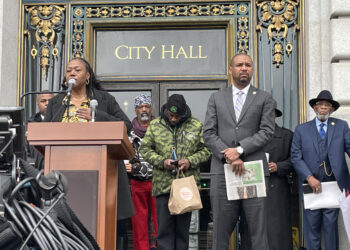 Tinisch Hollins, vice chair of the San Francisco African American Reparations Advisory Committee, addresses a crowd in support of reparations on the steps of San Francisco City Hall on Tuesday, March 14th, 2023. Hollins is flanked by San Francisco Board of Supervisors President Shamann Walton, who wrote legislation creating the committee. Photo credit: Daphne Young, Black News & Views.
