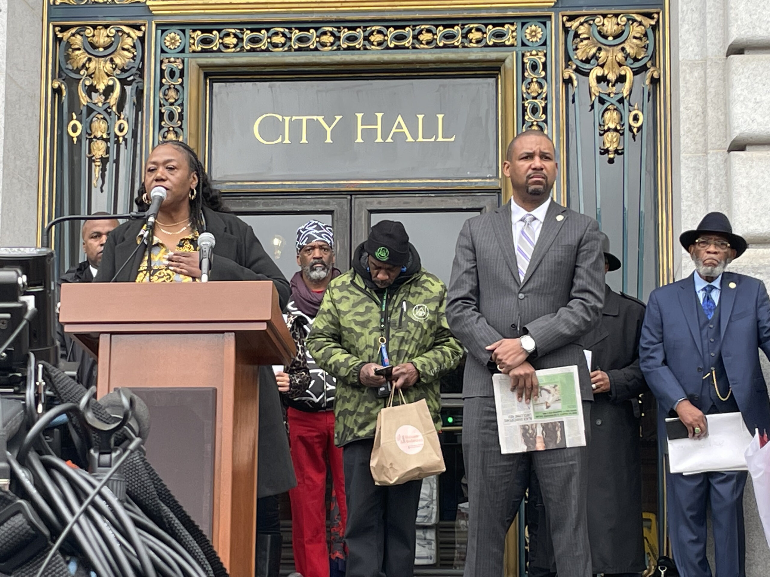Tinisch Hollins, vice chair of the San Francisco African American Reparations Advisory Committee, addresses a crowd in support of reparations on the steps of San Francisco City Hall on Tuesday, March 14th, 2023. Hollins is flanked by San Francisco Board of Supervisors President Shamann Walton, who wrote legislation creating the committee. Photo credit: Daphne Young, Black News & Views.