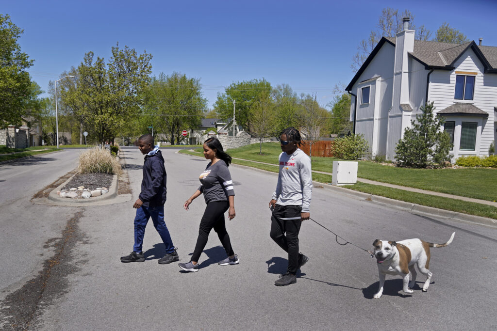 Kia Breaux and her sons John, 17, right, and Jaden, 14, walk the family dog, Lucky, in their Kansas City, Mo., neighborhood, Friday, April 21, 2023. The recent shooting of Black teenager Ralph Yarl by an 84-year-old white man when Yarl mistakenly went to the wrong address in a nearby neighborhood has shaken many Black residents in the predominantly white region of the city. Photo credit: Charlie Riedel, The Associated Press