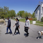 Kia Breaux and her sons John, 17, right, and Jaden, 14, walk the family dog, Lucky, in their Kansas City, Mo., neighborhood, Friday, April 21, 2023. The recent shooting of Black teenager Ralph Yarl by an 84-year-old white man when Yarl mistakenly went to the wrong address in a nearby neighborhood has shaken many Black residents in the predominantly white region of the city. Photo credit: Charlie Riedel, The Associated Press