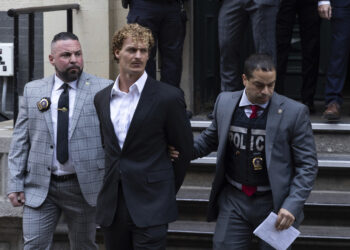 Daniel Penny, center, is walked by New York Police Department detectives out of the 5th Precinct on Friday, May. 12, 2023, in New York. Manhattan prosecutors announced Thursday they would bring the criminal charge against Penny, 24, a U.S. Marine Corps veteran, in the May 1 death of 30-year-old Jordan Neely. Photo credit: Jeenah Moon, The Associated Press