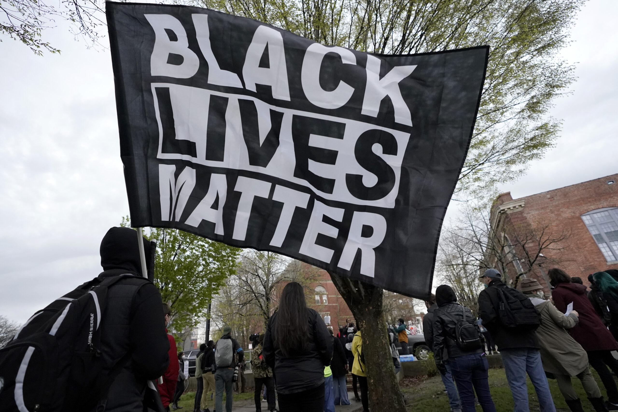 A demonstrator display a banner during a protest, Wednesday, April 21, 2021, in the Nubian Square neighborhood of Boston, a day after a guilty verdict was announced at the trial of former Minneapolis Police Officer Derek Chauvin for the 2020 death of George Floyd. Chauvin was convicted of murder and manslaughter Floyd's death. The demonstrators called for police reform and racial equality. Photo credit: Steven Senne
