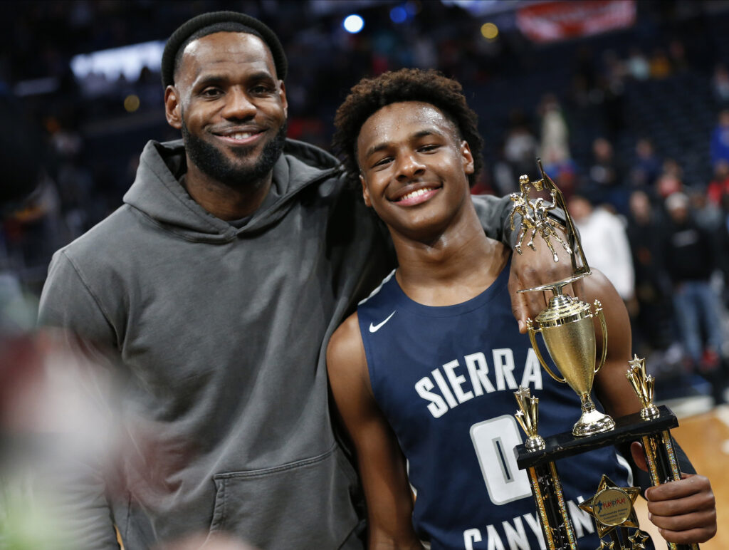 LeBron James, left, poses with his son, Bronny, after Sierra Canyon beat Akron St. Vincent - St. Mary in a high school basketball game, Saturday, Dec. 14, 2019, in Columbus, Ohio. Bronny James was released from Cedars-Sinai Medical Center in Los Angeles after suffering a cardiac arrest during basketball practice on Monday, July 24, 2023, at the University of Southern California earlier in the week. Photo credit: Jay LaPrete, The Associated Press