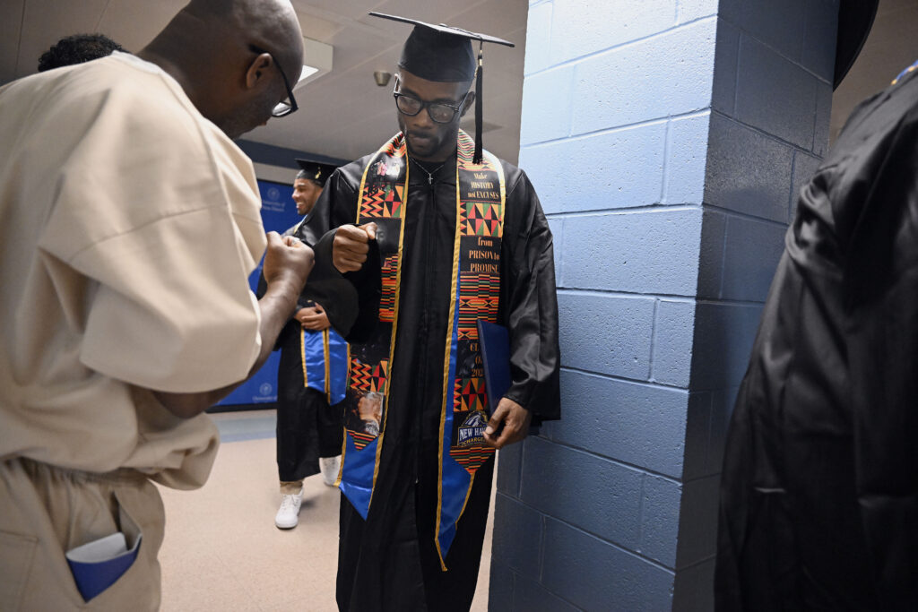 Marcus Harvin, right, fist bumps an inmate and fellow student at the first-ever college graduation ceremony at MacDougall-Walker Correctional Institution, Friday, June 9, 2023, in Suffield, Connecticut. The ceremony was held under a partnership established in 2021 by the University of New Haven and the Yale Prison Education Initiative. Photo credit: Jessica Hill, The 