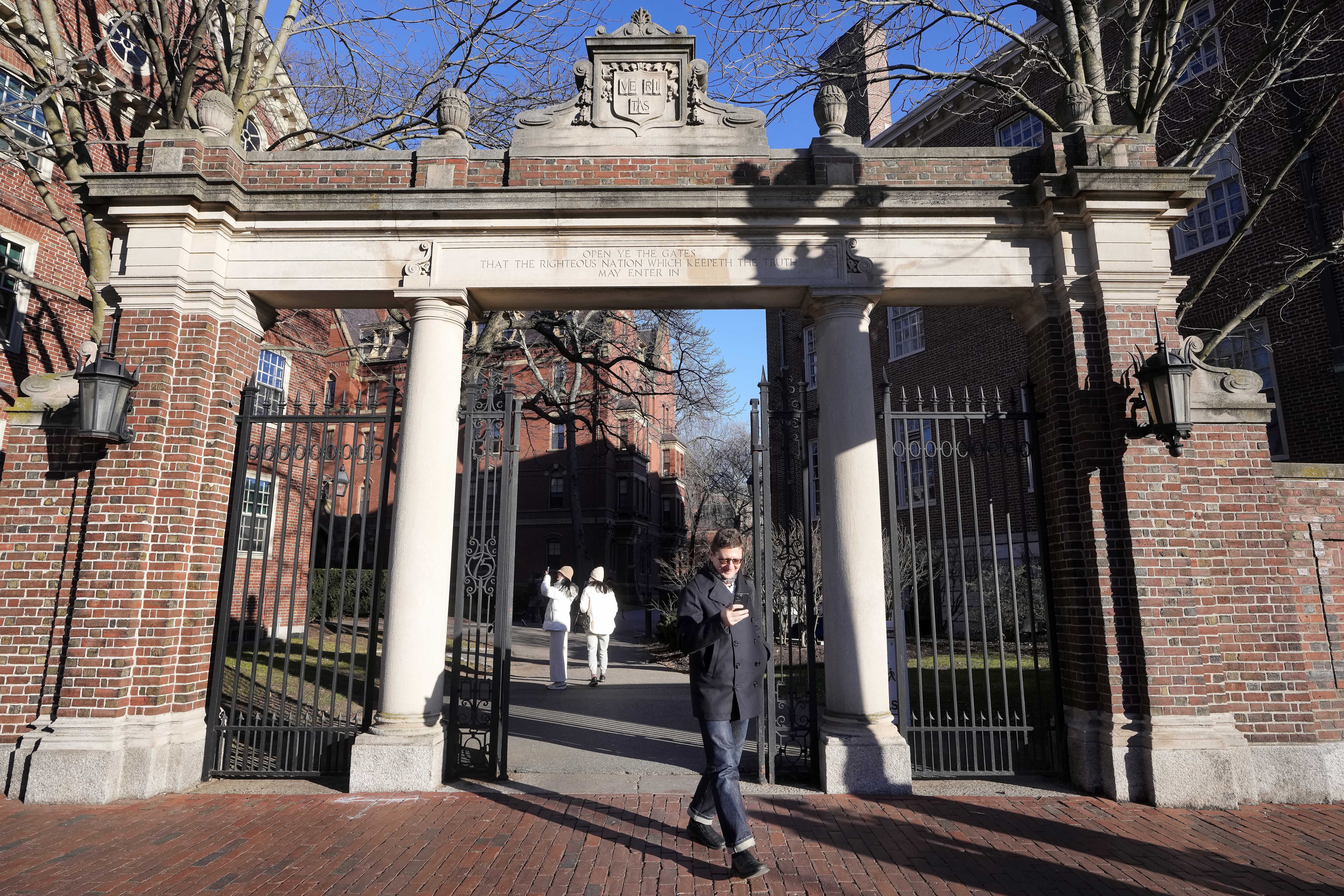 A passer-by walks through a gate to the Harvard University campus, Tuesday, Jan. 2, 2024, in Cambridge, Massachusetts. Harvard University President Claudine Gay resigned Tuesday amid plagiarism accusations and criticism over testimony at a congressional hearing where she was unable to say unequivocally that calls on campus for the genocide of Jews would violate the school's conduct policy. Photo credit: Steven Senne, The Associated Press