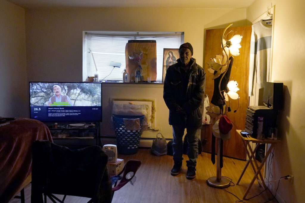 Rudolph Williams stands for a portrait in his apartment bedroom Monday, Jan. 8, 2024, in Harvey, Illinois. Williams was home in the Chicago south suburb when he realized that the doors and windows to his courtyard-style apartment had been boarded up with plywood, locking him inside. Photo credit: Charles Rex Arbogast, The Associated Press