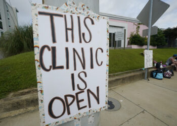 A posted sign outside the Jackson Women's Health Organization clinic assures potential patients that it is open, Sunday, July 3, 2022, in Jackson, Mississippi. The clinic is the only facility that performs abortions in the state. On June 24, 2022, the U.S. Supreme Court overturned Roe v. Wade, ending constitutional protections for abortion. Photo credit: Rogelio V. Solis, The Associated Press