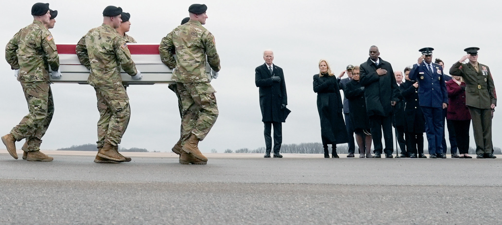President Joe Biden, standing from left, and First Lady Jill Biden, watch as an Army carry team moves the transfer case containing the remains of U.S. Army Sgt. William Jerome Rivers, 46, of Carrollton, Ga., at Dover Air Force Base, Delaware, Friday, Feb. 2, 2024. Rivers was killed in a drone attack in Jordan on Jan. 28. Photo credit: Matt Rourke, The Associated Press