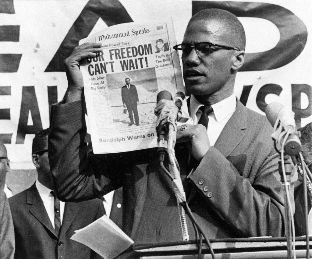 Malcolm X holds up a paper for the crowd to see during a Black Muslim rally in New York City on Aug. 6, 1963.  Photo credit: The Associated Press