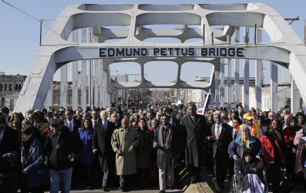 Then-Vice President Joe Biden and late U.S. Rep. John Lewis, D-Ga., lead a group across the Edmund Pettus Bridge in Selma, Alabama, March 3, 2013.  Photo credit: Dave Martin, The Associated Press