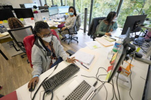 Contact tracers, from left to right, Christella Uwera, Dishell Freeman and Alejandra Camarillo talk about a case at Harris County Public Health contact tracing facility, Thursday, June 25, 2020, in Houston. Photo credit: David J. Phillip, The Associated Press