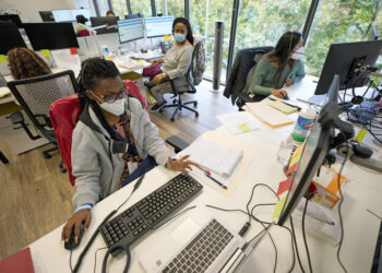 Contact tracers, from left to right, Christella Uwera, Dishell Freeman and Alejandra Camarillo talk about a case at Harris County Public Health contact tracing facility, Thursday, June 25, 2020, in Houston. Photo credit: David J. Phillip, The Associated Press