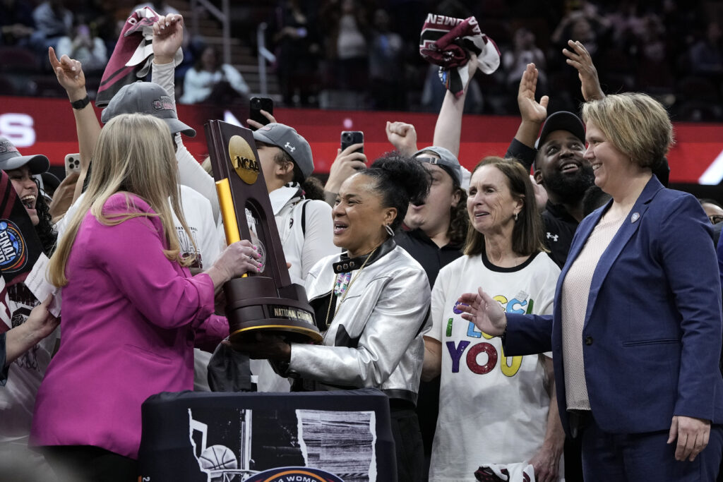 Dawn Staley, the University of South Carolina head women's basketball coach, center, celebrates with the trophy after the Final Four college basketball championship game against Iowa in the women's NCAA tournament on Sunday, April 7, 2024, in Cleveland, Ohio. South Carolina won 87-75. Photo credit: Morry Gash, The Associated Press