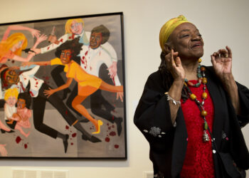 Late artist Faith Ringgold talks about her artwork in front of her painting, "Die (1967)" during a press preview of her exhibition, "American People, Black Light: Faith Ringgold's Paintings of the 1960s" at the National Museum of Women in the Arts in Washington, D.C., on June 19, 2013. Ringgold, an award-winning author and artist who broke down barriers for Black female artists and became famous for her richly colored and detailed quilts combining painting, textiles and storytelling, died Friday, April 12, 2024, at her home in Englewood, New Jersey. She was 93. Photo credit: Jacquelyn Martin, The Associated Press