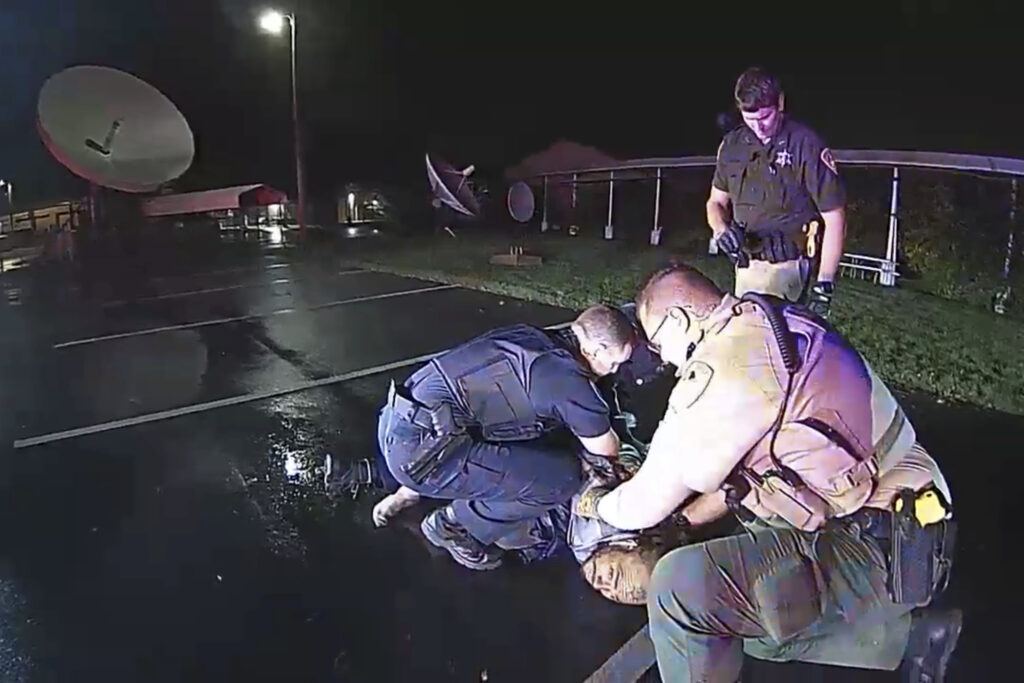 In this image from Altoona Police Department body-camera video, police restrain Demetrio Jackson in a parking lot on the border of Altoona and Eau Claire, Wisconsin, on Oct. 8, 2021, minutes before a paramedic injects him with ketamine. Five medical experts who reviewed the case for AP said Jackson’s behavior did not appear to be dangerous enough to justify the use of ketamine. Photo credit: Altoona Police Department via The Associated Press