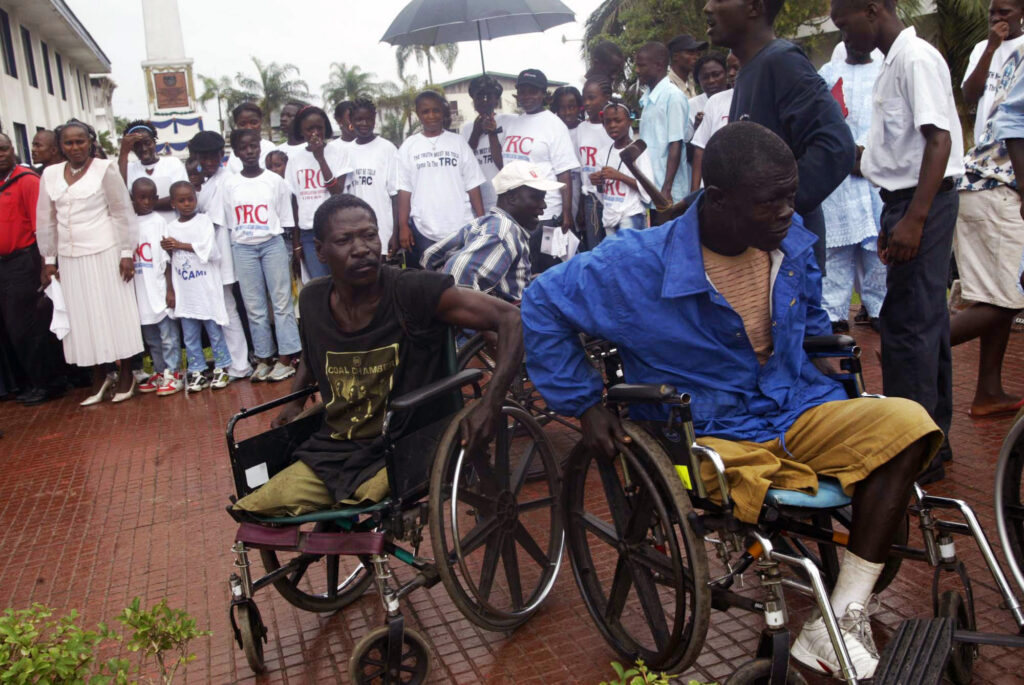 Two war victims seen in wheelchairs at the launch of Liberia's Truth and Reconciliation Commission in the city of Monrovia, Liberia, Thursday, June 22, 2006. Then-President Ellen Johnson Sirleaf officially launched Liberia's Truth and Reconciliation Commission, saying a full accounting of atrocities committed during nearly a quarter century of conflict will set the stage for long-term peace. Now, in 2024, Liberian lawmakers are pushing forward with a proposal to set up a war crimes court. Photo credit: Pewee Flomoku, The Associated Press