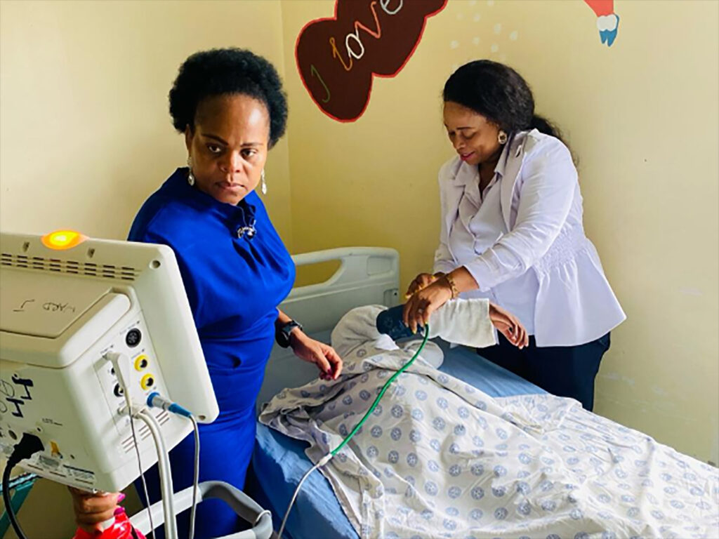 This photo supplied by the Government Health Department, Limpopo, South Africa, shows Dr. Phophi Ramathuba, left, member of the executive council for health, and a staff member at an undisclosed hospital, Friday, March 29, 2023, where they attend to the 8-year-old sole survivor of a bus crash that killed at least 45 people. Forensic investigators in South Africa are searching for the bodies of victims after a bus carrying pilgrims to an Easter gathering plunged off a bridge and caught fire. Photo credit: South African Health Department via The Associated Press