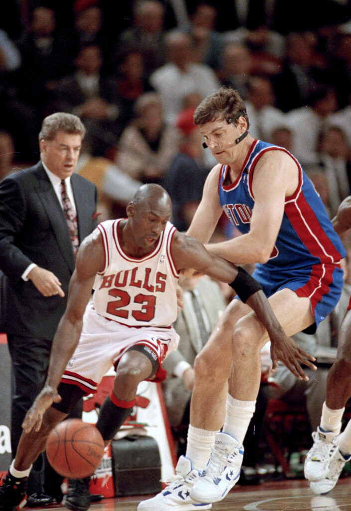 The Chicago Bulls' Michael Jordan (then number 23) moves around the Detroit Pistons' Bill Laimbeer (40) during the first quarter of their playoff game in Chicago, May 21, 1991. Pistons coach Chuck Daly watches in the background. Photo credit: John Swart, The Associated Press
