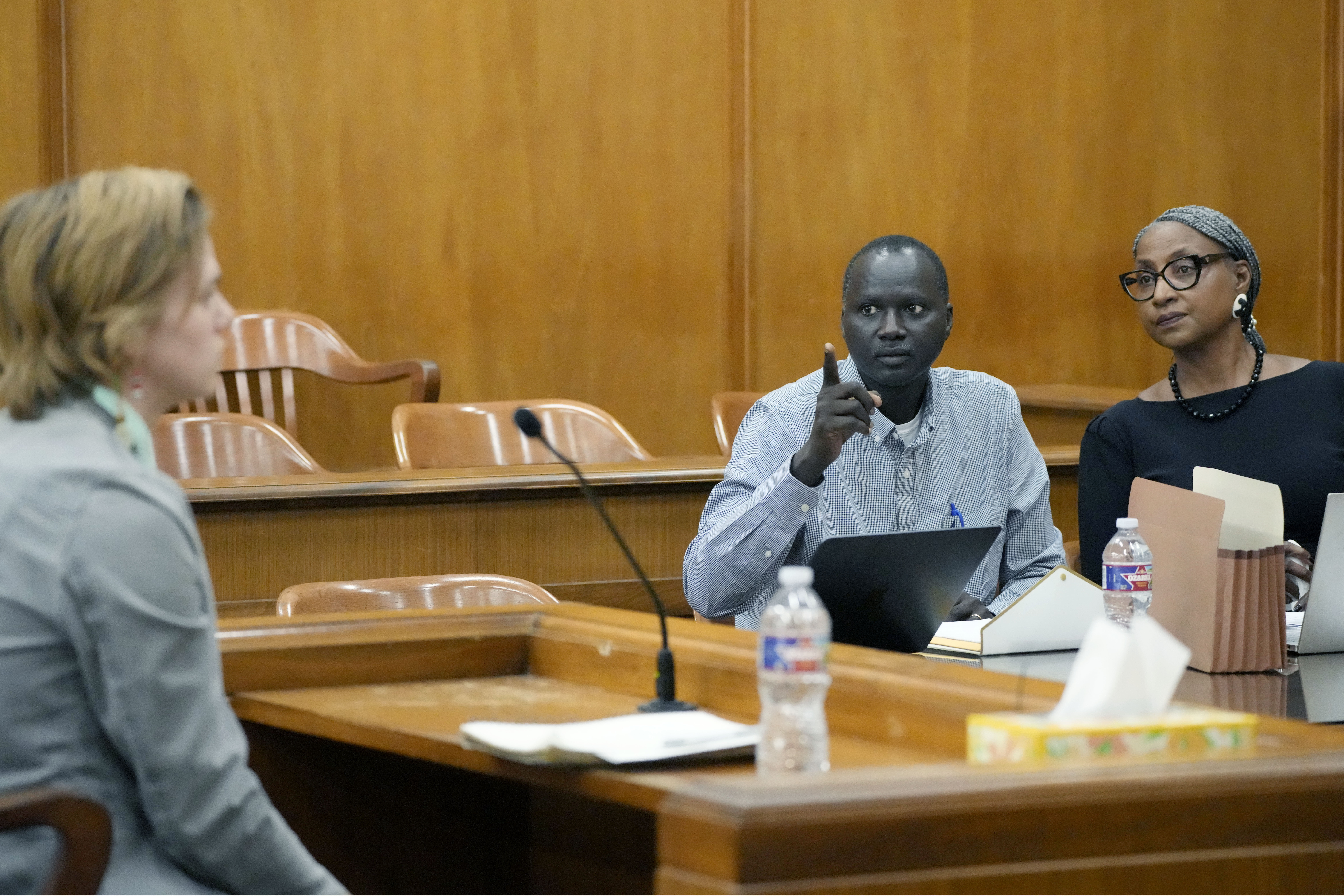 Lisa Ross, right, attorney for Bul Mabil, seated center, brother of Dau Mabil, a 33-year-old Jackson, Mississippi, resident who went missing on March 25 and whose body was found in April floating in the Pearl River in Lawrence County, listens to his question, while Karissa Bowley, wife of the deceased, awaits a renewed spate of questions during a hearing, on whether a judge should dissolve or modify his injunction preventing the release of Mabil's remains until an independent autopsy could be conducted, Tuesday, April 30, 2024, in Jackson. Photo credit: Rogelio V. Solis, The Associated Press