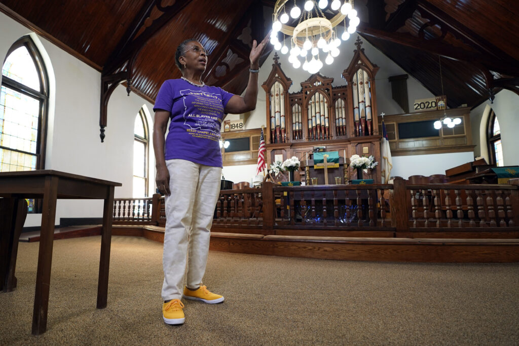 Sharon Gillins talks about the history of the Reedy Chapel African Methodist Episcopal Church, Wednesday, June 17, 2020, in Galveston, Texas. The church's origins date back to 1848 when black slaves were given the land by their white owners for a place of worship. It also continues to host a Juneteenth celebration that is attended by the community. Photo credit: David J. Phillip, The Associated Press