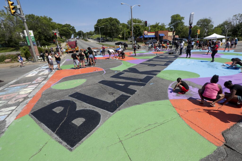 People paint the intersection of Locust and Martin Luther King Drive during a Juneteenth event Friday, June 19, 2020, in Milwaukee. Juneteenth marks the day in 1865 when federal troops arrived in Galveston, Texas, to take control of the state and ensure all enslaved people be freed, more than two years after the Emancipation Proclamation. Photo credit: Morry Gash, The Associated Press