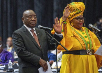 South African président Cyril Ramaphosa raises his hand as he is sworn is as a member of Parliament ahead of the vote by lawmakers to reelect him as leader of the country in Cape Town, South Africa, Friday, June 14, 2024. At right is Pemmy Majodina, an ANC lawmaker. Photo credit: Jerome Delay, The Associated Press