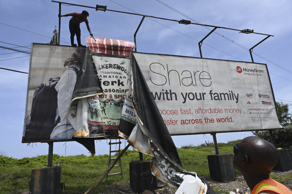Workers dismantle an advertisement board to protect it from Hurricane Beryl in Kingston, Jamaica, on Tuesday, July 2, 2024. Photo credit: Collin Reid, The Associated Press