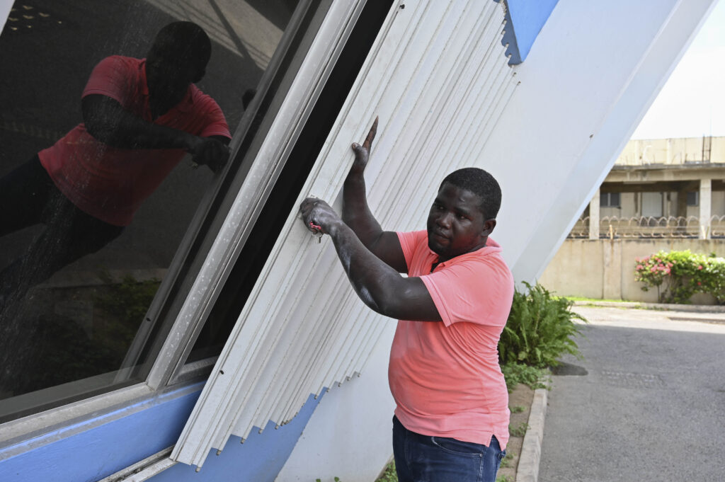 A man covers the windows of a building to protect it from the incoming Hurricane Beryl in Kingston, Jamaica, on Tuesday, July 2, 2024. Photo credit: Collin Reid, The Associated Press