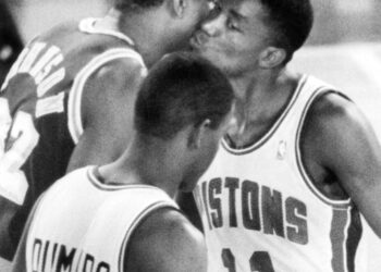 The Los Angeles Lakers' Earvin Johnson, left, and the Detroit Pistons Isiah Thomas, right, exchange greetings prior to the start of the NBA Finals game at the Silverdome in Pontiac, Michigan, on June 16, 1988. In the foreground is Detroit's Joe Dumars. Photo credit: Richard Sheinwald, The Associated Press