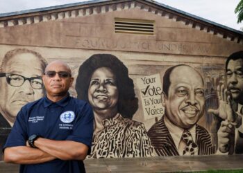 Kenneth Kilpatrick, president of the Brownsville Civic Neighborhood Association, poses with a mural of neighborhood historical figures on Wednesday, July 23, 2025 in the Brownsville neighborhood of Miami, Fla. Kilpatrick thinks there more pros than cons to becoming a city. “There’s enough dormant space to bring in [needed resources]…and make sure our money doesn’t leave the city,” said Kilpatrick. Photo credit: The Miami Herald
