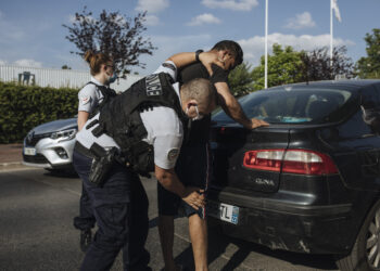 A police officer searches an immigrant in Garges-les-Gonesse, a suburb of Paris, on June, 15, 2021. Photo credit: Lewis Joly, The Associated Press
