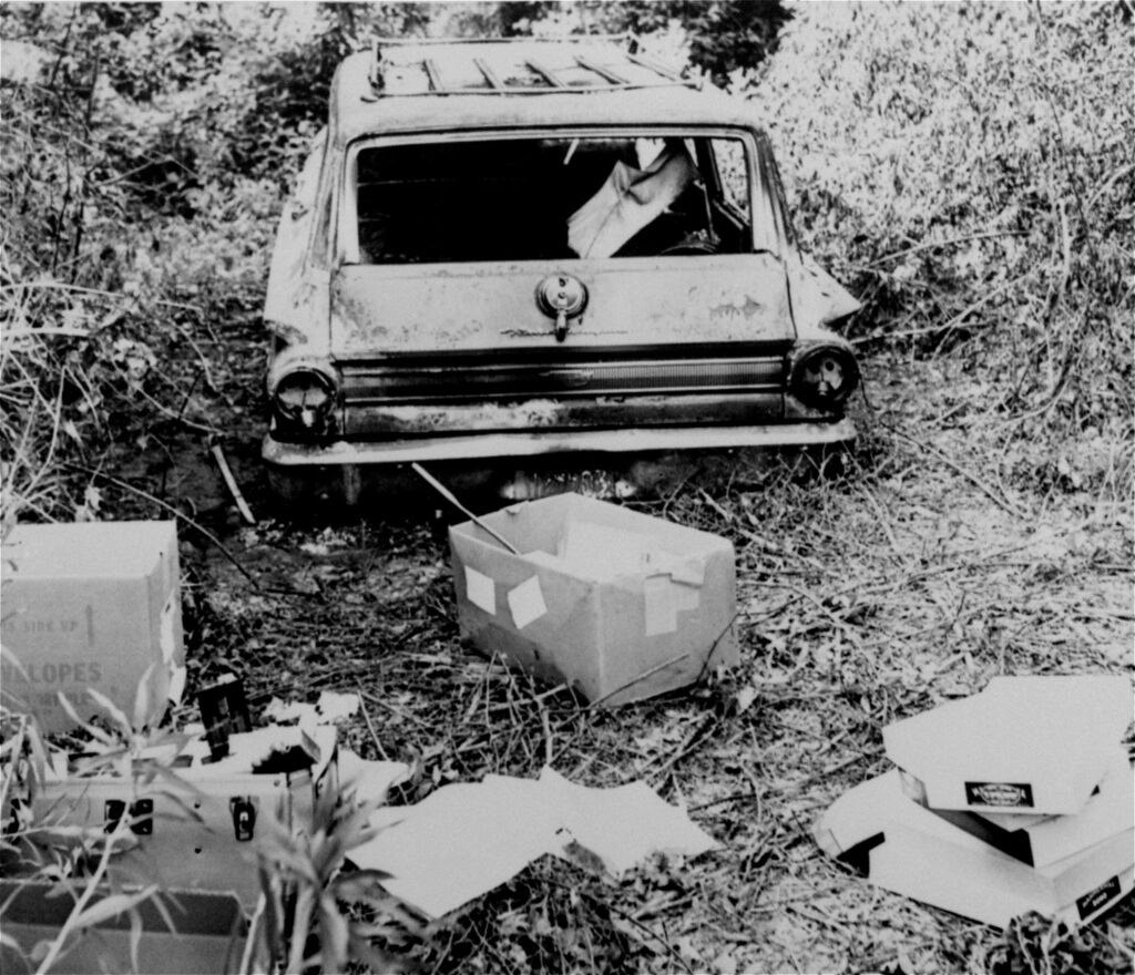 This June 24, 1964, file photo shows the burned station wagon of civil rights workers James Chaney, Andrew Goodman, and Michael Schwerner in a swampy area near Philadelphia, Mississippi. The bodies of the men were found later in an earthen dam. Photo credit, Jack Thornell, The Associated Press