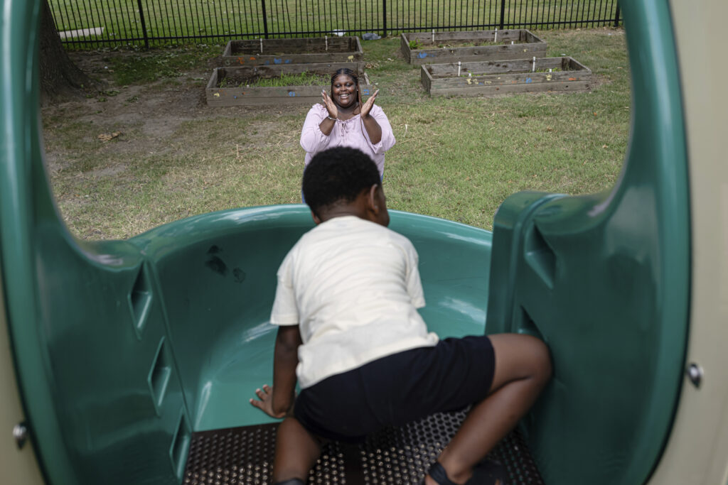 Aaliyah Barnes cheers as her son, Aarmoni Barnes, plays on the playground at the Stoddard Johnston Scholar House on Friday, July 11, 2025, in Louisville, Kentucky. Photo credit: Jon Cherry, The Associated Press