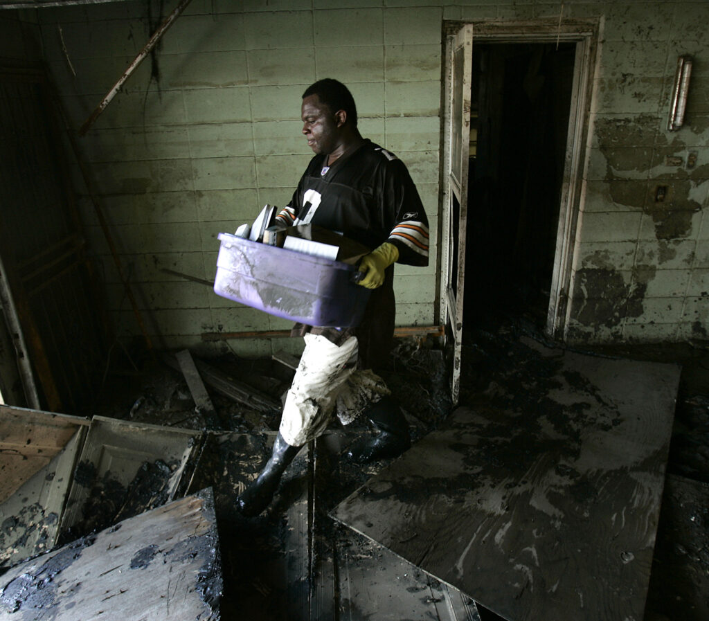 Tony Reid carries belongings from his flood-damaged home in the Lower Ninth Ward of New Orleans on Oct. 3, 2005. Photo credit: Charlie Riedel, The Associated Press