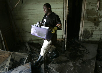 Tony Reid carries belongings from his flood-damaged home in the Lower Ninth Ward of New Orleans on Oct. 3, 2005. Photo credit: Charlie Riedel, The Associated Press