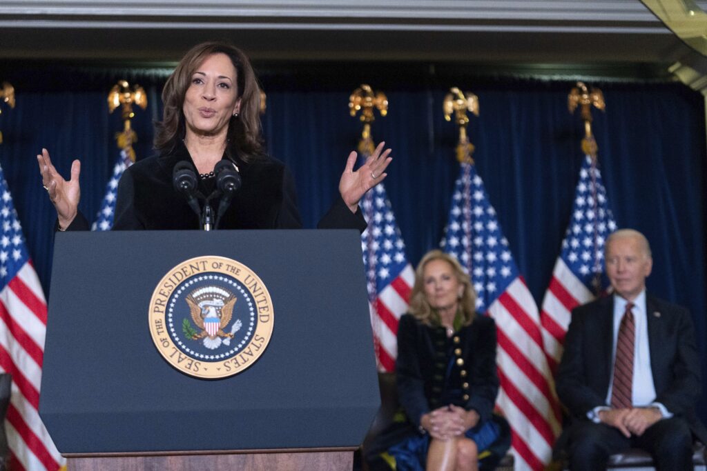 Former Vice President Kamala Harris delivers remarks as former First Lady Jill Biden and former President Joe Biden look on at the Democratic National Committee's Holiday Reception at the Willard Hotel in Washington, D.C., on Dec. 15, 2024. Photo credit: Jose Luis Magana, The Associated Press