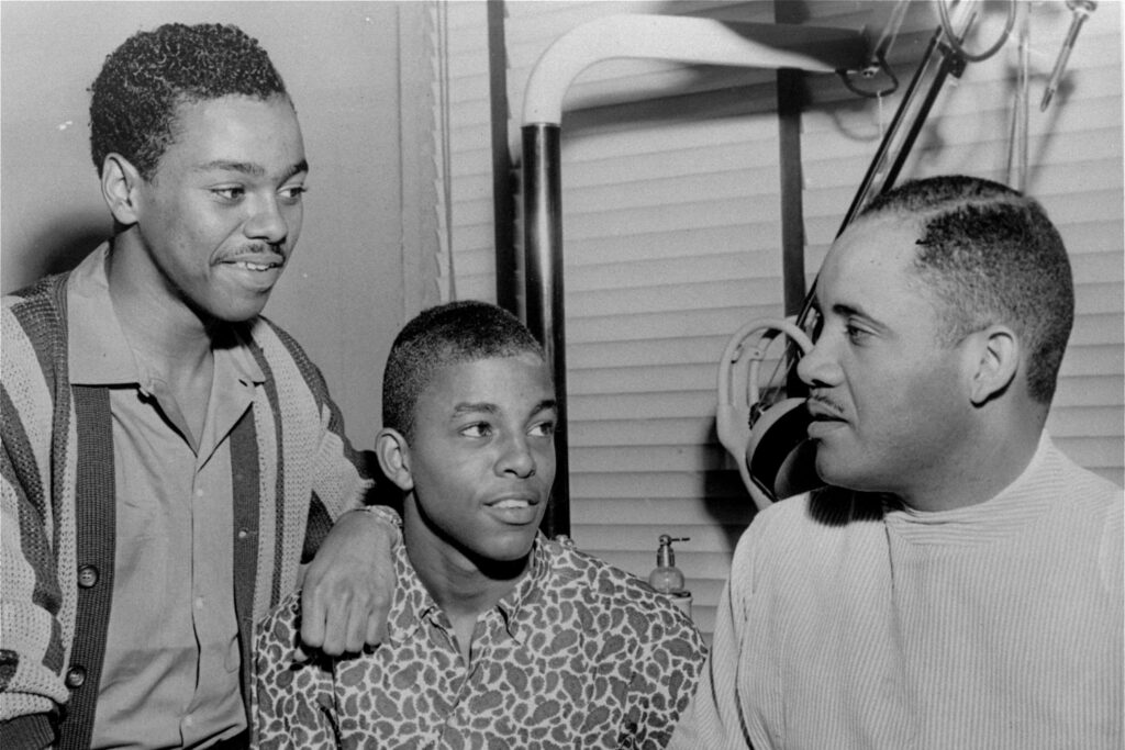 Joseph McNeil, left, standing next to Ezell Blair, Jr., center, student leader in the original lunch counter sit-down demonstration, discusse legal aspects of anti-segregation with Dr. George C. Simkins, right, Greensboro dentist and local NAACP leader, in Greensboro, N.C., April 20, 1960. Photo credit: News & Record via The Associated Press