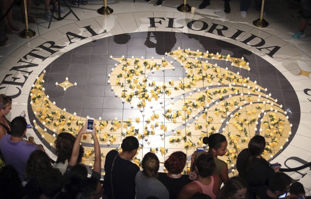 Students gather around lit candles surrounding the University of Central Florida logo on June 14, 2016. Photo credit: Stephen M. Dowell, Orlando Sentinel via The Associated Press