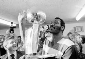 Washington Bullets player Elvin Hayes holds the NBA Championship trophy in the crowded locker room after the Bullets defeated Seattle to win the NBA title in Seattle, Washington, on June 7, 1978. Photo credit: The Associated Press