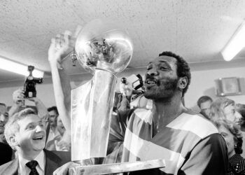 Washington Bullets player Elvin Hayes holds the NBA Championship trophy in the crowded locker room after the Bullets defeated Seattle to win the NBA title in Seattle, Washington, on June 7, 1978. Photo credit: The Associated Press