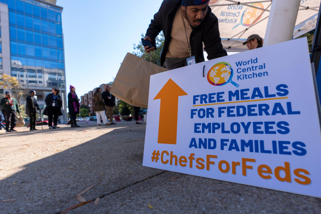 A person gets a bottle of water to go with a meal distributed by chef Jose Andres' World Central Kitchen for federal workers and their families in Canal Park on Monday, Oct. 27, 2025, in Washington, D.C. Photo credit: Alex Brandon, The Associated Press