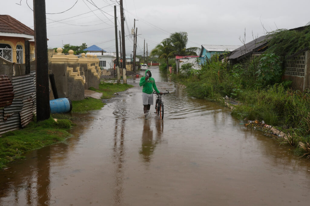 A man wades through a flooded street ahead of the predicted arrival of Hurricane Melissa in Old Harbour, Jamaica, on Monday, Oct. 27, 2025. Photo credit: Matias Delacroix, The Associated Press
