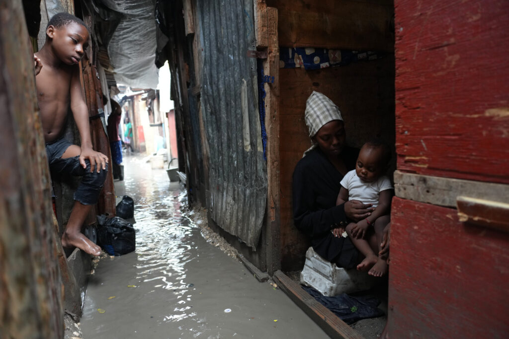 People huddle inside a shelter for families displaced by gang violence, flooded by rain brought by Hurricane Melissa, in Port-au-Prince, Haiti on Wednesday, Oct. 29, 2025. Photo credit: Odelyn Joseph, The Associated Press