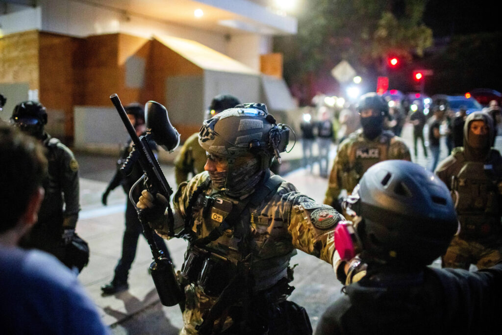 Police and federal officers stand guard an area by the U.S. Immigration and Customs Enforcement facility in Portland, Oregon, on Sunday, Oct. 5, 2025. Photo credit: Ethan Swope, The Associated Press