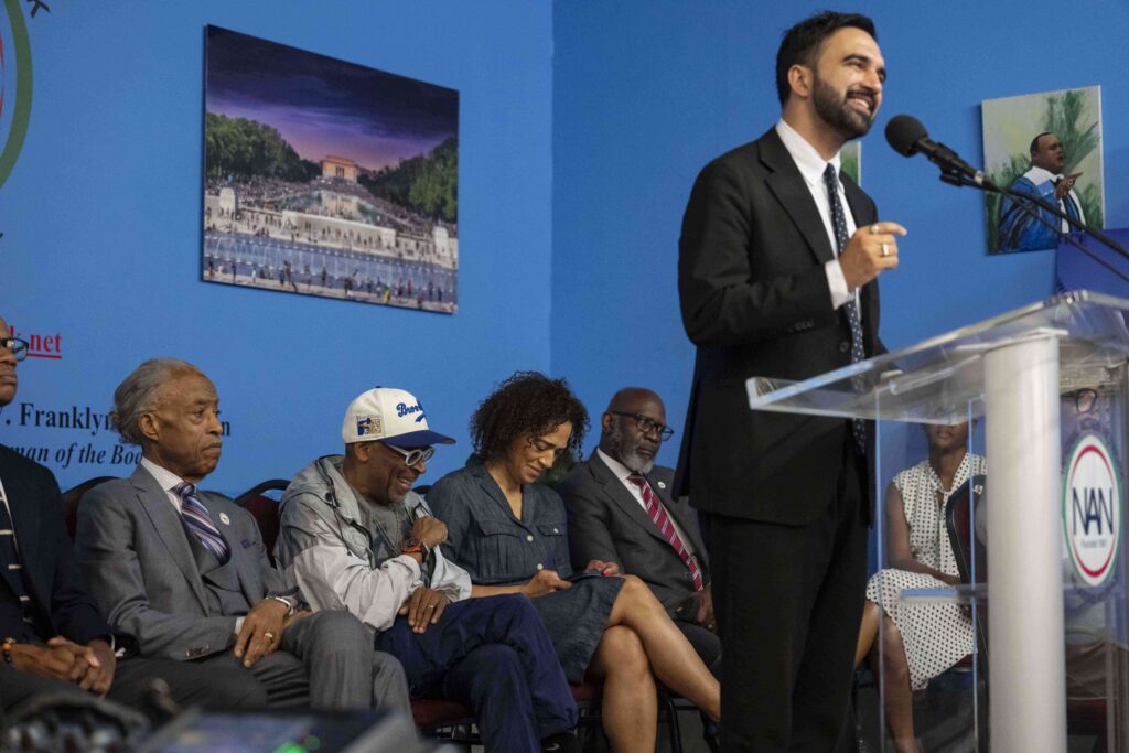 NYC's Democratic mayoral candidate, Zohran Mamdani, right, speaks during a National Action Network rally in Harlem as Spike Lee and the Rev. Al Sharpton listen on June 28, 2025, in New York. Photo credit: Yuki Iwamura, The Associated Press