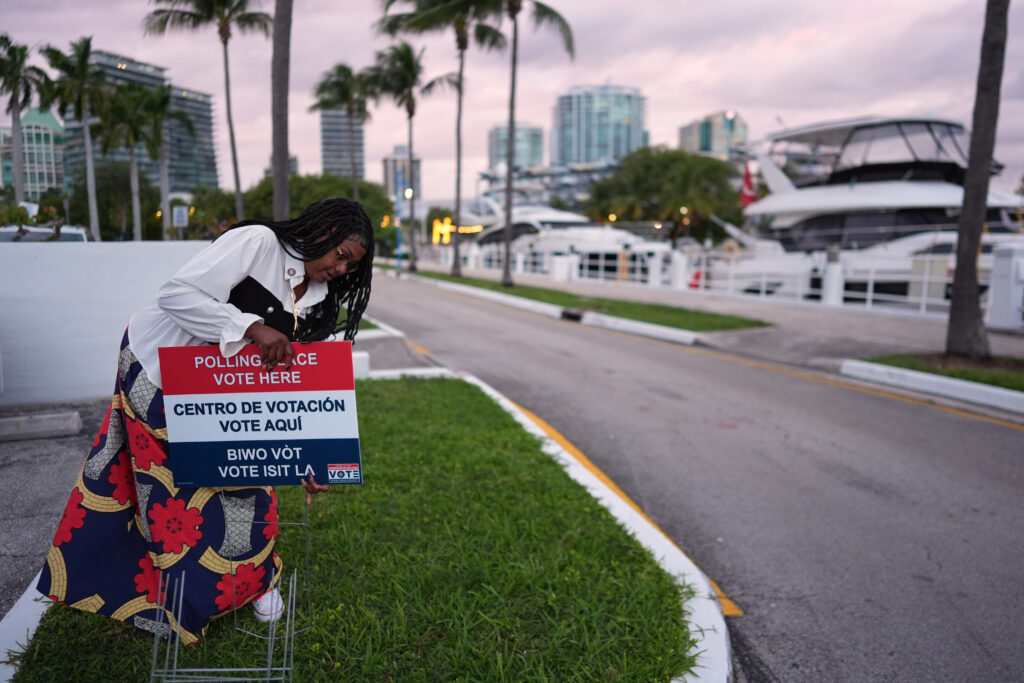 Polling place supervisor Bridget Knighton installs a sign directing voters to a voting site at Miami City Hall on Tuesday, Nov. 4, 2025, in Miami. Photo credit: Rebecca Blackwell, The Associated Press